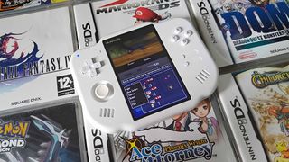 MagicX Zero 40 handheld on top of Nintendo DS game boxes with Dragon Quest Monsters Joker gameplay on screen.