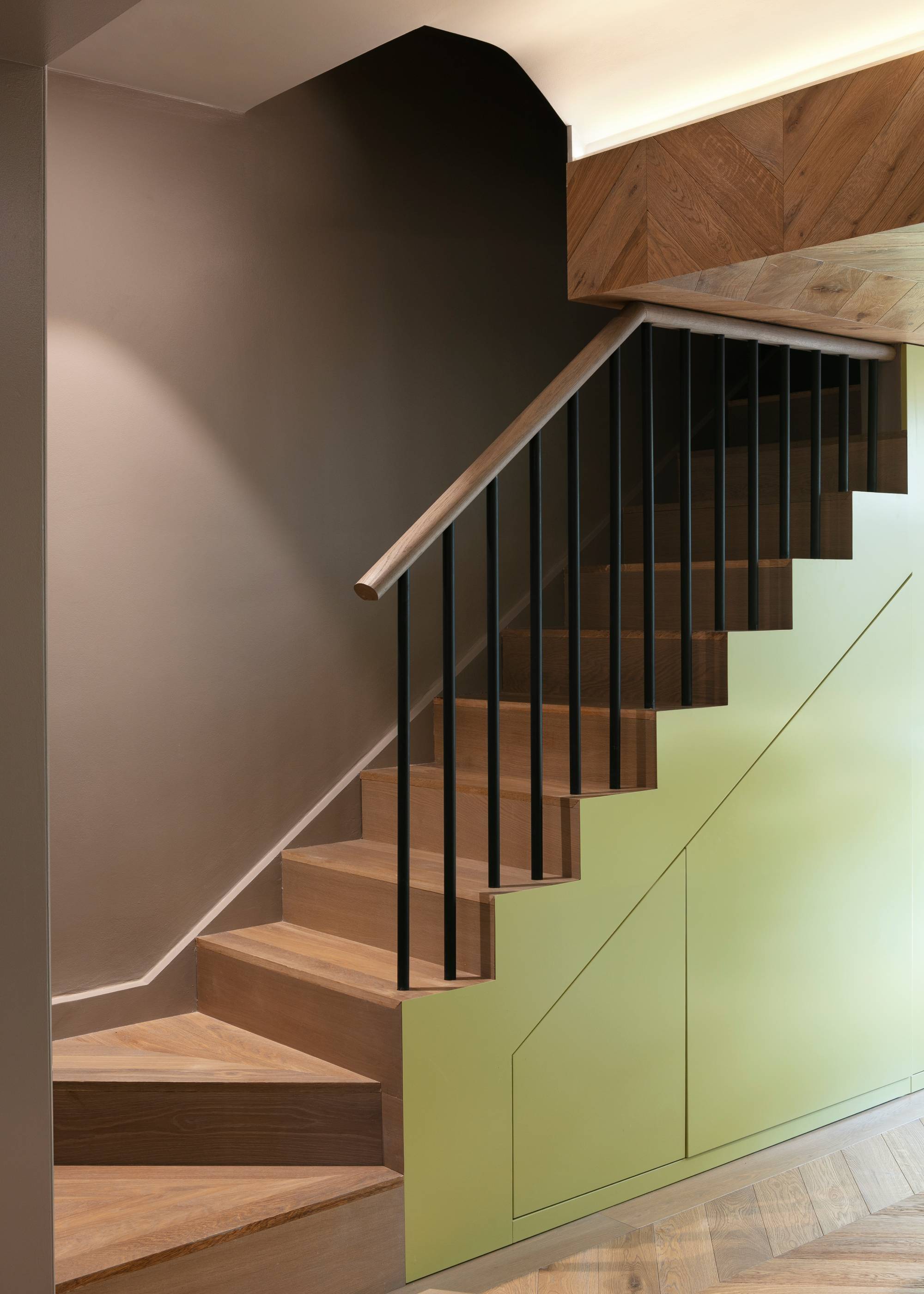 green and wood staircase with wall lighting