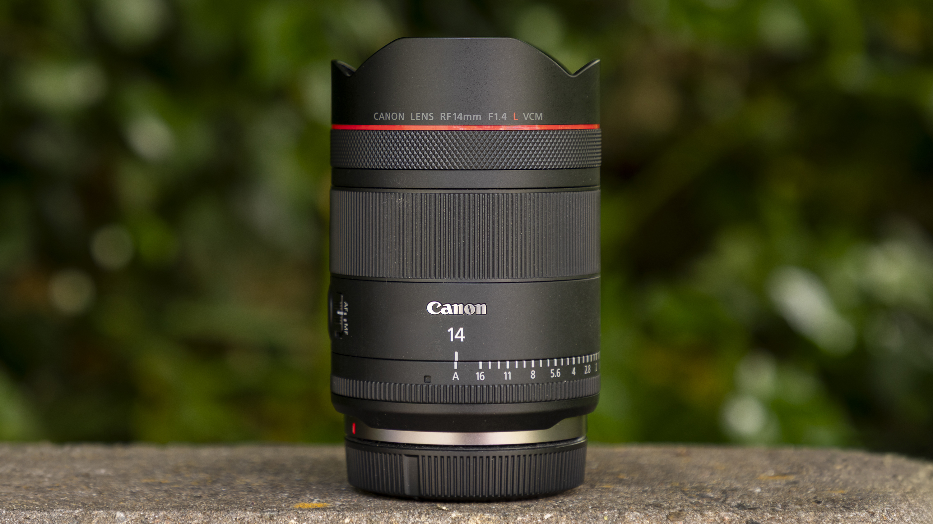 Canon RF 14mm f/1.4L VCM lens on wall with greenery behind