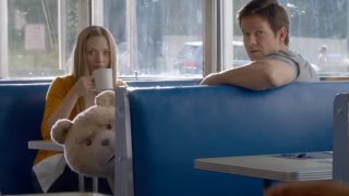 Amanda Seyfried and Mark Wahlberg sit in a diner booth with looks of concern in Ted 2.