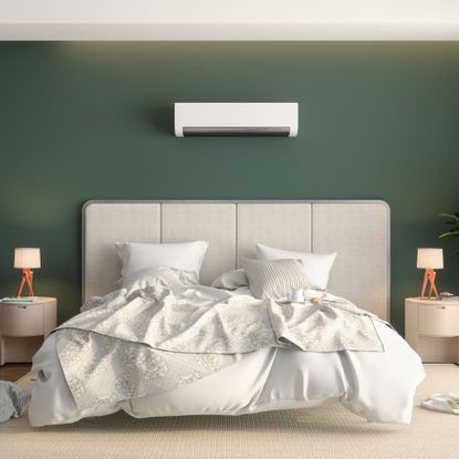 air conditioning unit on a dark green wall above a large bed with light headboard and bedding, and two side tables with small lamps