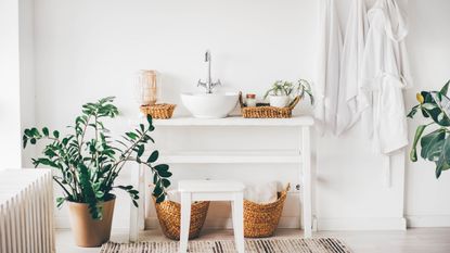 White bathroom with large plant and wicker baskets