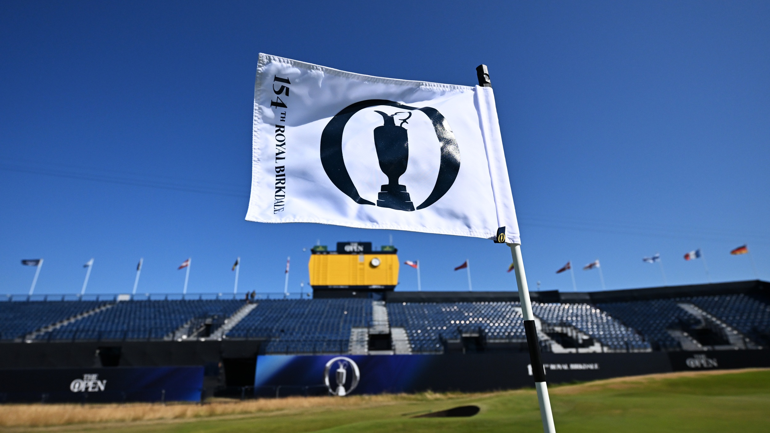 A flag in the breeze in front of a grandstand at The Open Championship at Royal Birkdale