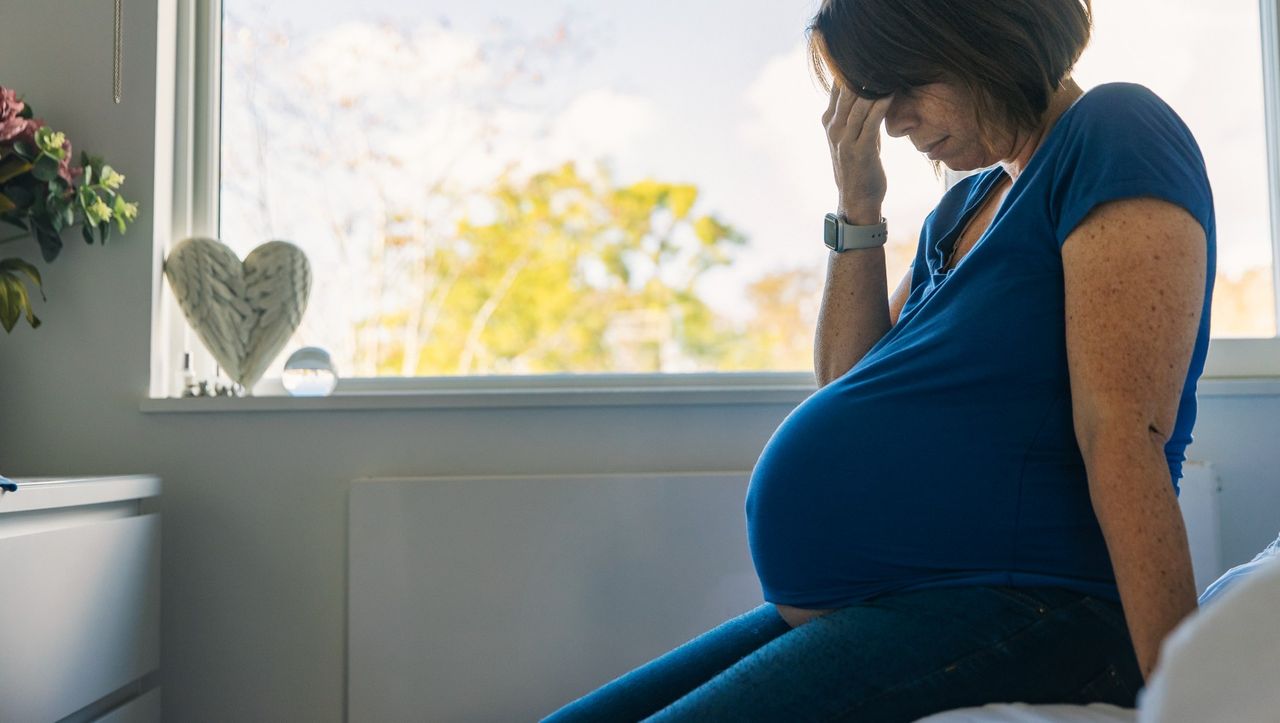 A pregnant woman sitting on a bed