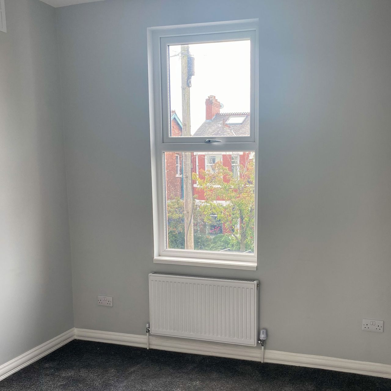 Bare grey room with window and white radiator