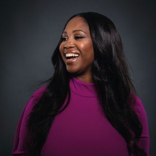 Motsi Mabuse in a pink purple turtleneck, laughing and looking off camera