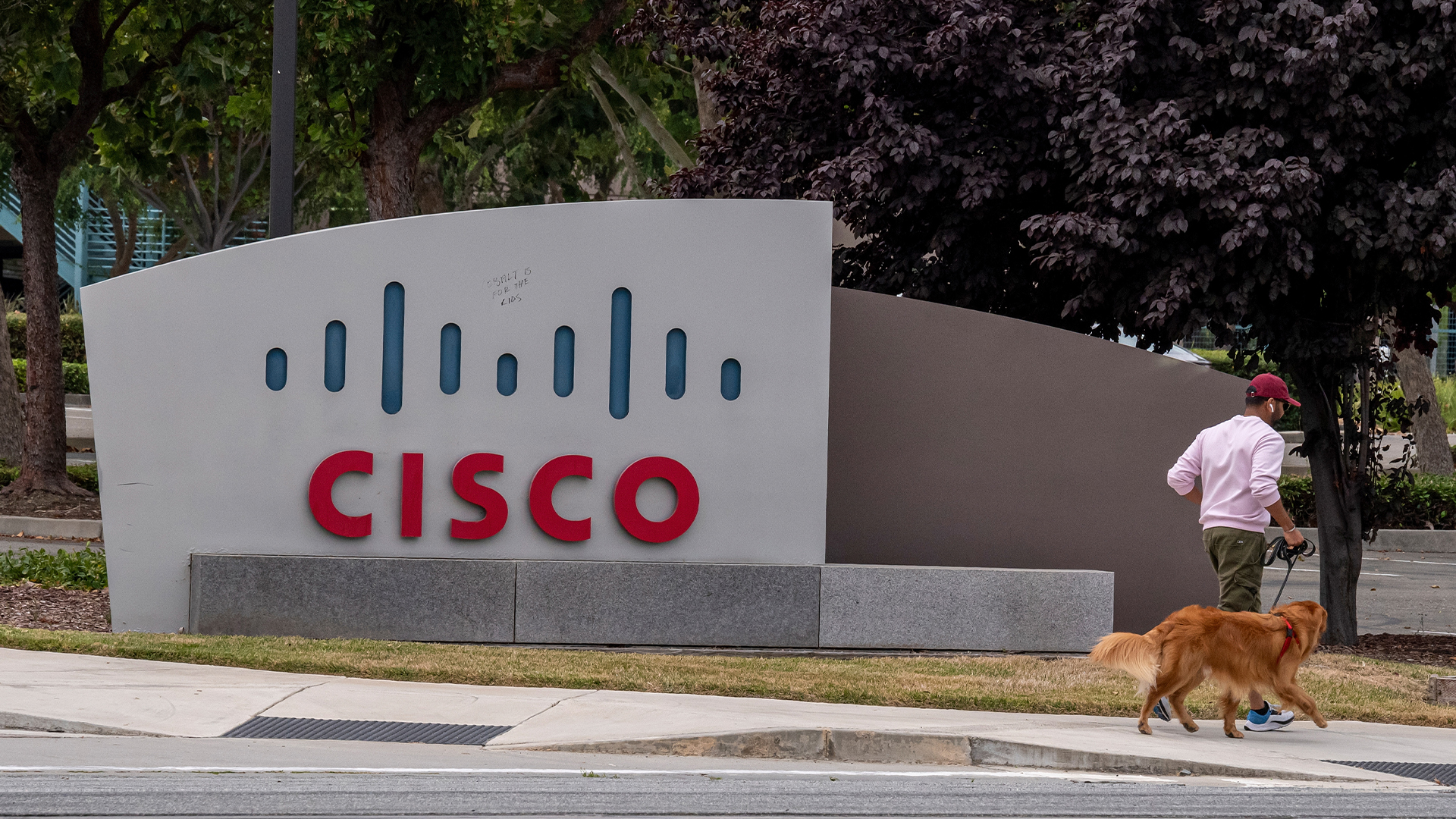 Man pictured walking past Cisco sign at the company headquarters in San Jose, California.