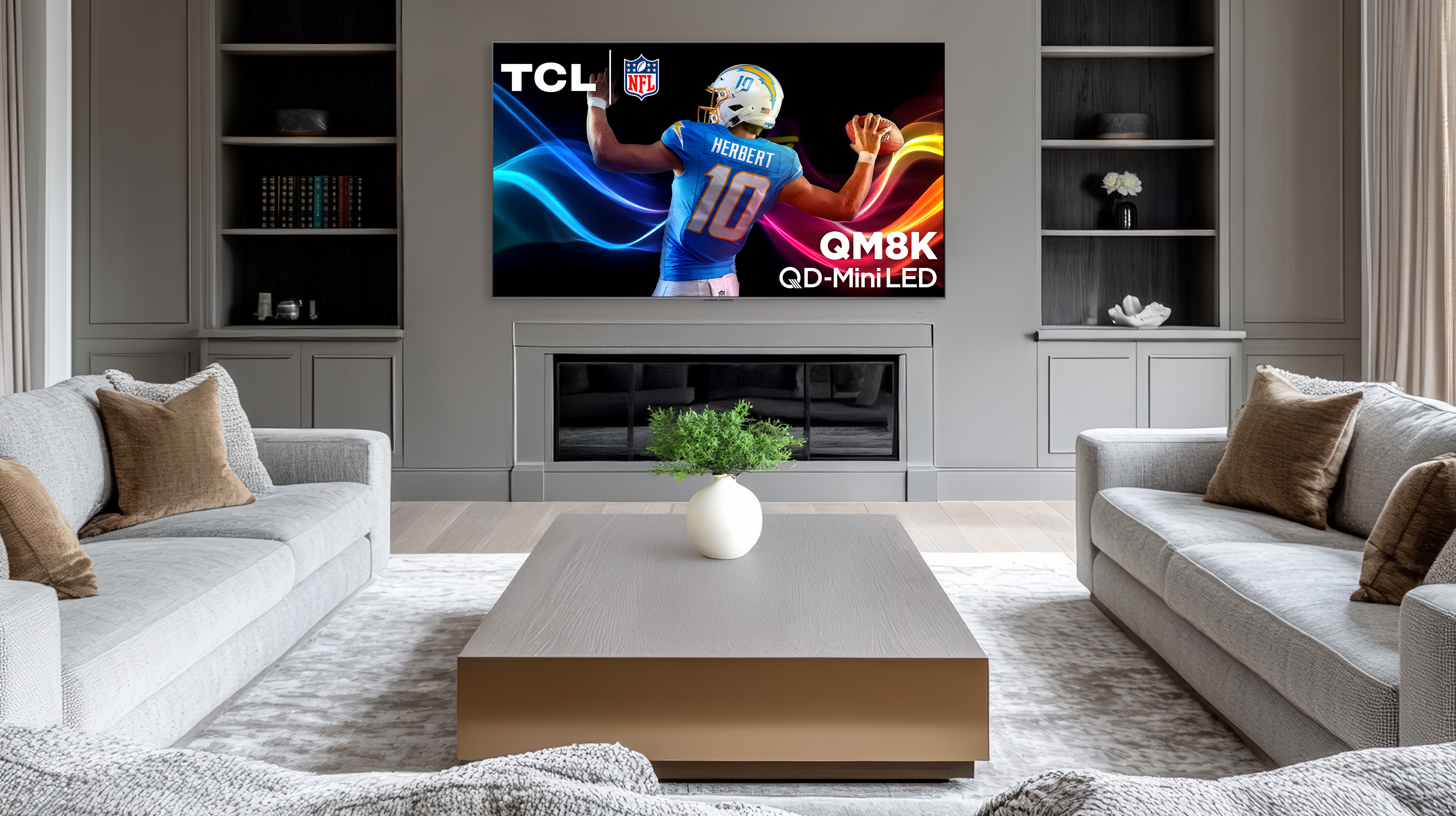 The TCL QM8K in a white living room showing a graphic of a man playing american football