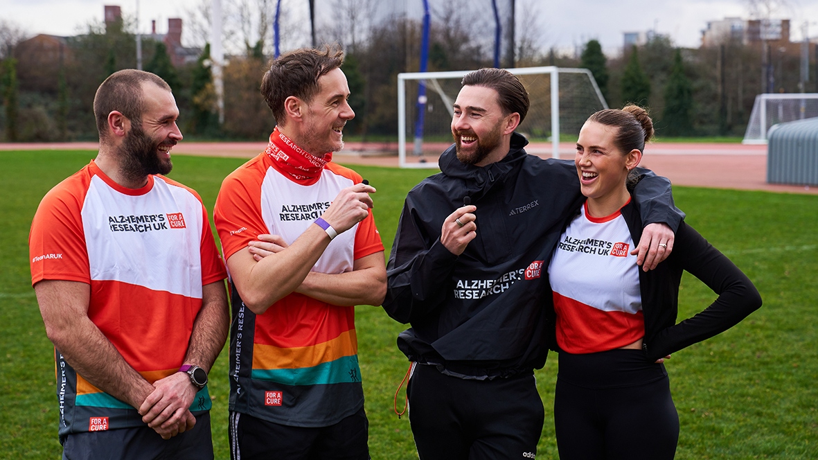 Team Quirke from left to right: James, Andrew Knott, Charlie Quirke and Chloe. They are all smiling and looking at each other, dressed in running gear and standing on a football pitch.