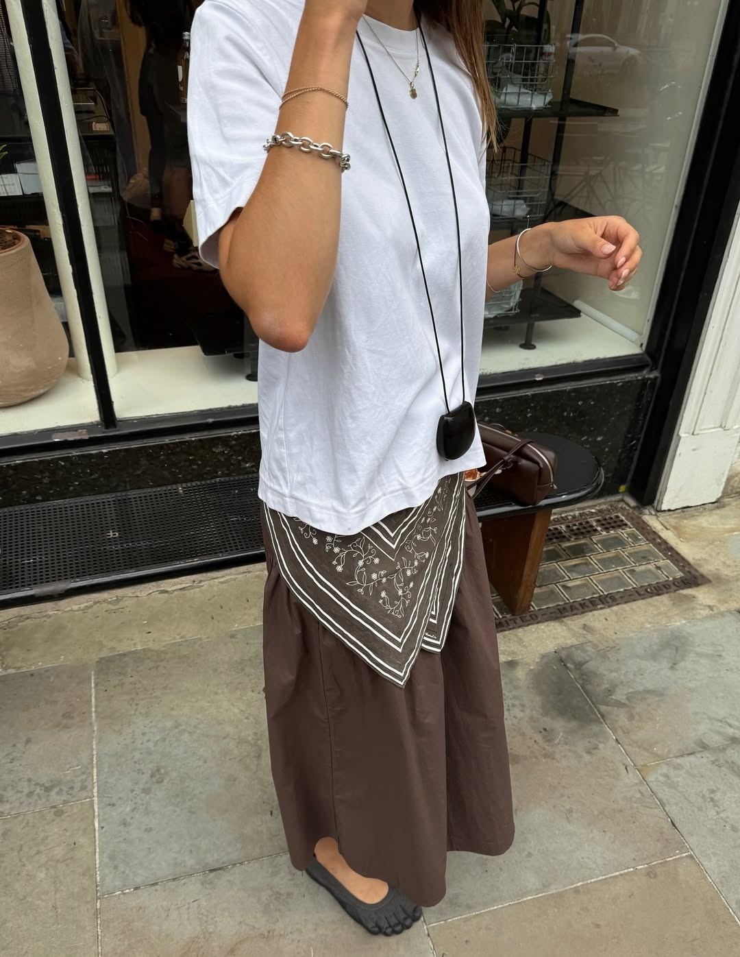 Influencer Poppy Almond wears a silk scarf tied around her waist with a brown poplin skirt and white crewneck tee.