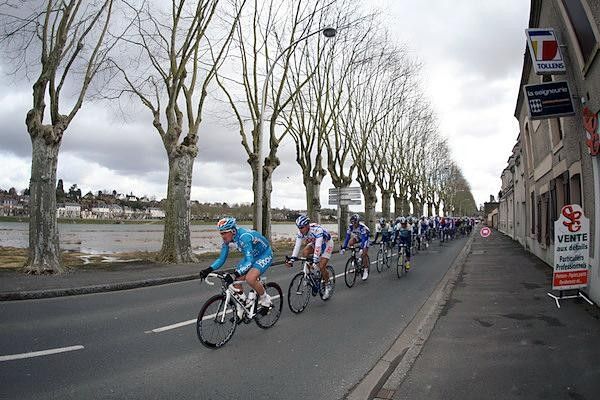 The peloton races through early-season France where the trees are still in winter training.