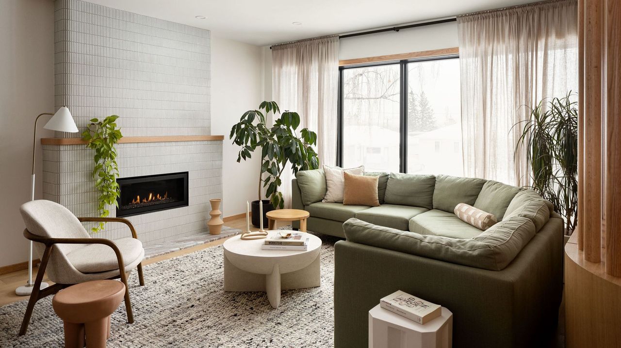 living room with white walls, rounded green sofa, and rounded tiled fireplace