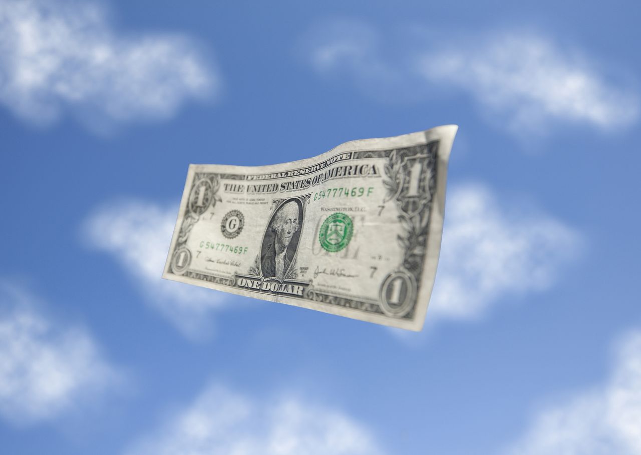 a US dollar bill floating in the blue sky