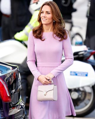 Kate Middleton wearing a pink long sleeved dress and white handbag