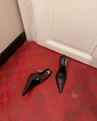 Photo of @iliridakrasniqi's Saint Laurent brown and gold slingback heels on a red, tile floor.