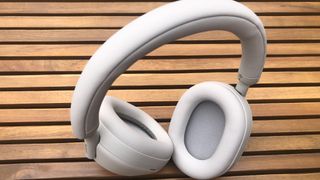 Sony XM5 headphones in ecru (off white) placed outdoors on a garden table