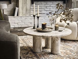 marble style coffee table in a contemporary boho style living room with exposed whitewashed brick wall