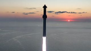 a large rocket launches into a dawn sky from a seaside pad