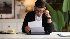 Man at a desk looking surprised at the contents of a letter