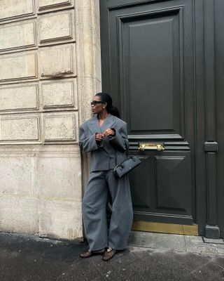 Marilyn Nwawulor-Kazemaks wearing a gray suit with a Alaïa Le Teckel bag.