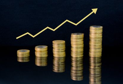 Stacks of coins on black background with arrow leading upward