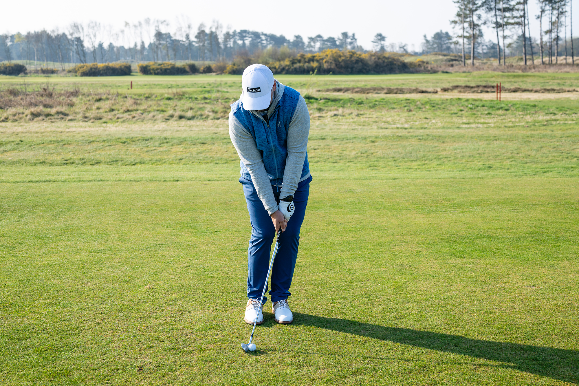 Peter Finch at address preparing to hit a low chip and run shot, with hands and weight forwards and ball position back on the trail foot