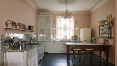 A kitchen with pastel tones used throughout. There is also a mini kitchen island/ dining area in the kitchen.