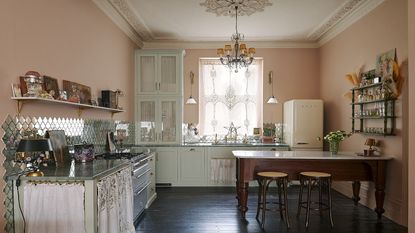A kitchen with pastel tones used throughout. There is also a mini kitchen island/ dining area in the kitchen. 