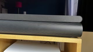 En svart Sonos Arc bredvid en Samsung S900B soundbar på en TV-bänk.