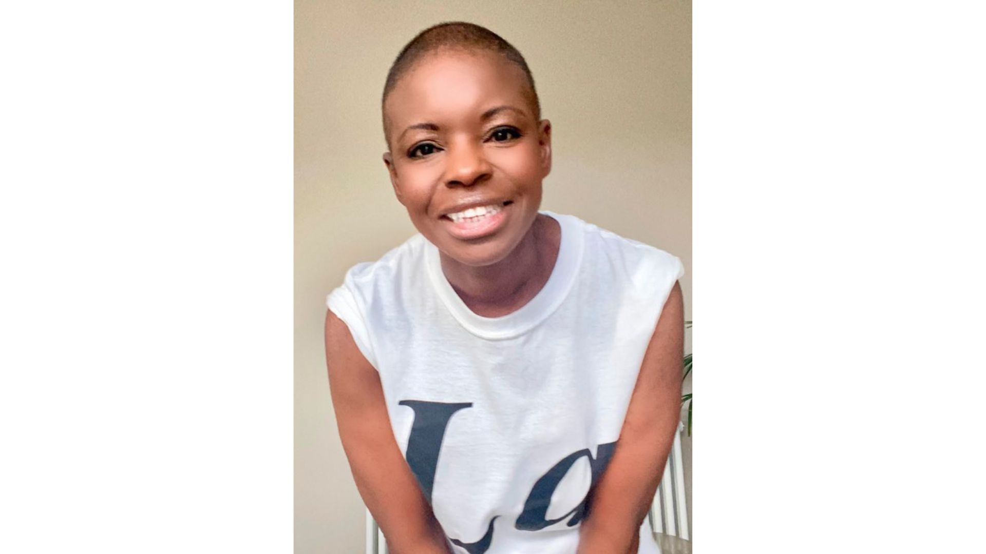 A smiling woman wears a t-shirt. Her hair has been shaved very short