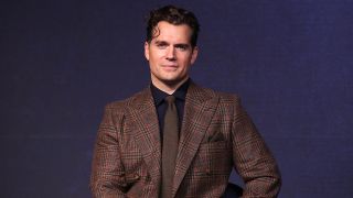 Henry Cavill in a brown suit looking at the camera ahead of an Argylle press event. 