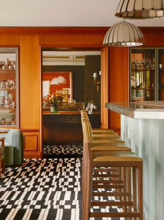 In a vibrantly decorated restaurant, orange walls, tiled flooring, soft upholstered seating, and beautiful pendant lights create a homely atmosphere.