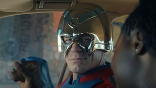 A silver-helmeted superhero sitting in a car