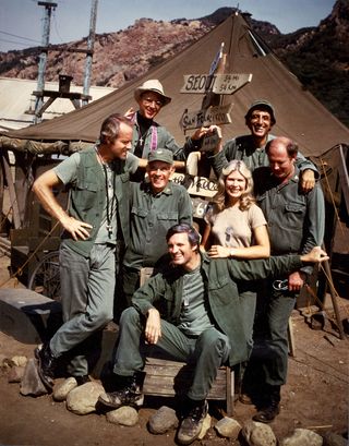 a promo shot of M*A*S*H featuring a group of soldiers on a military base