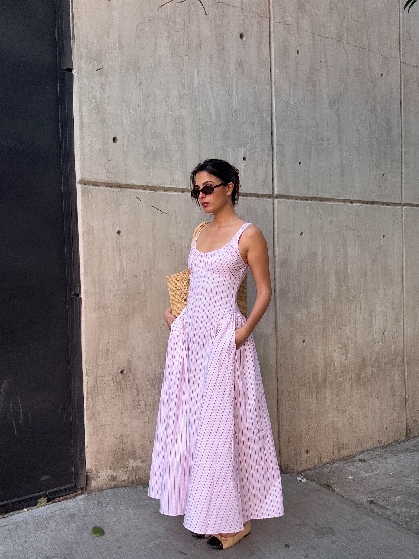 French influencer wearing a long pink striped drop-waist dress with cap-toe ballet flats