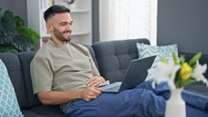 A man sitting on a sofa in a relaxed way and using a laptop