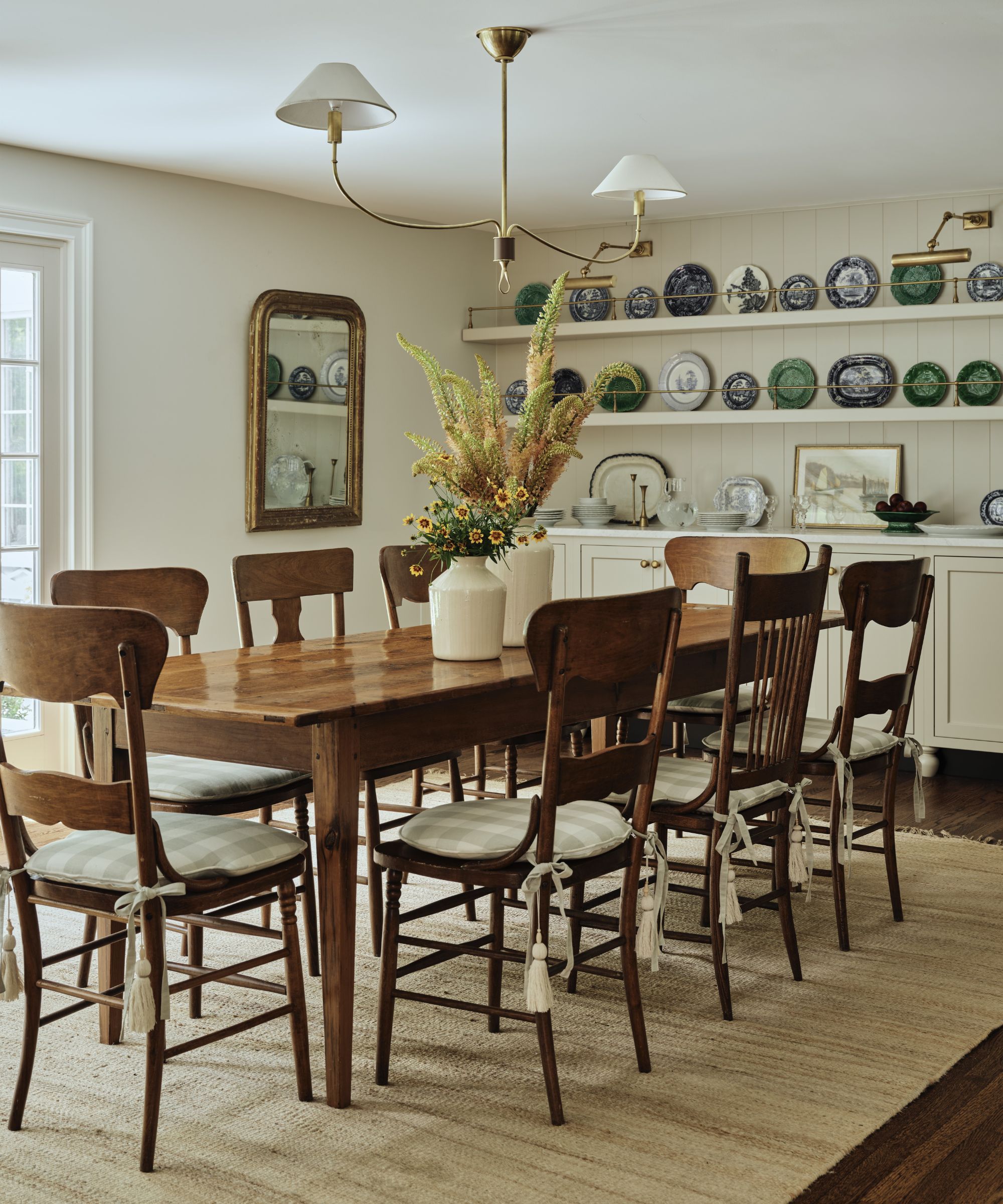 a warm neutral kitchen breakfast table with a vintage plate wall and rustic farmhouse furnishings