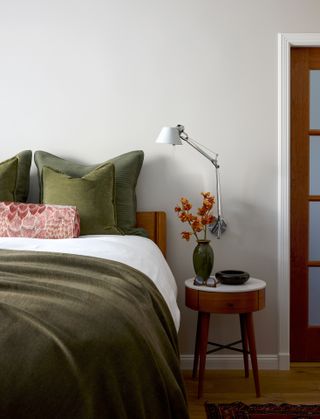 Bedroom with green duvet and walls painted in Benjamin Moore Pale Oak.