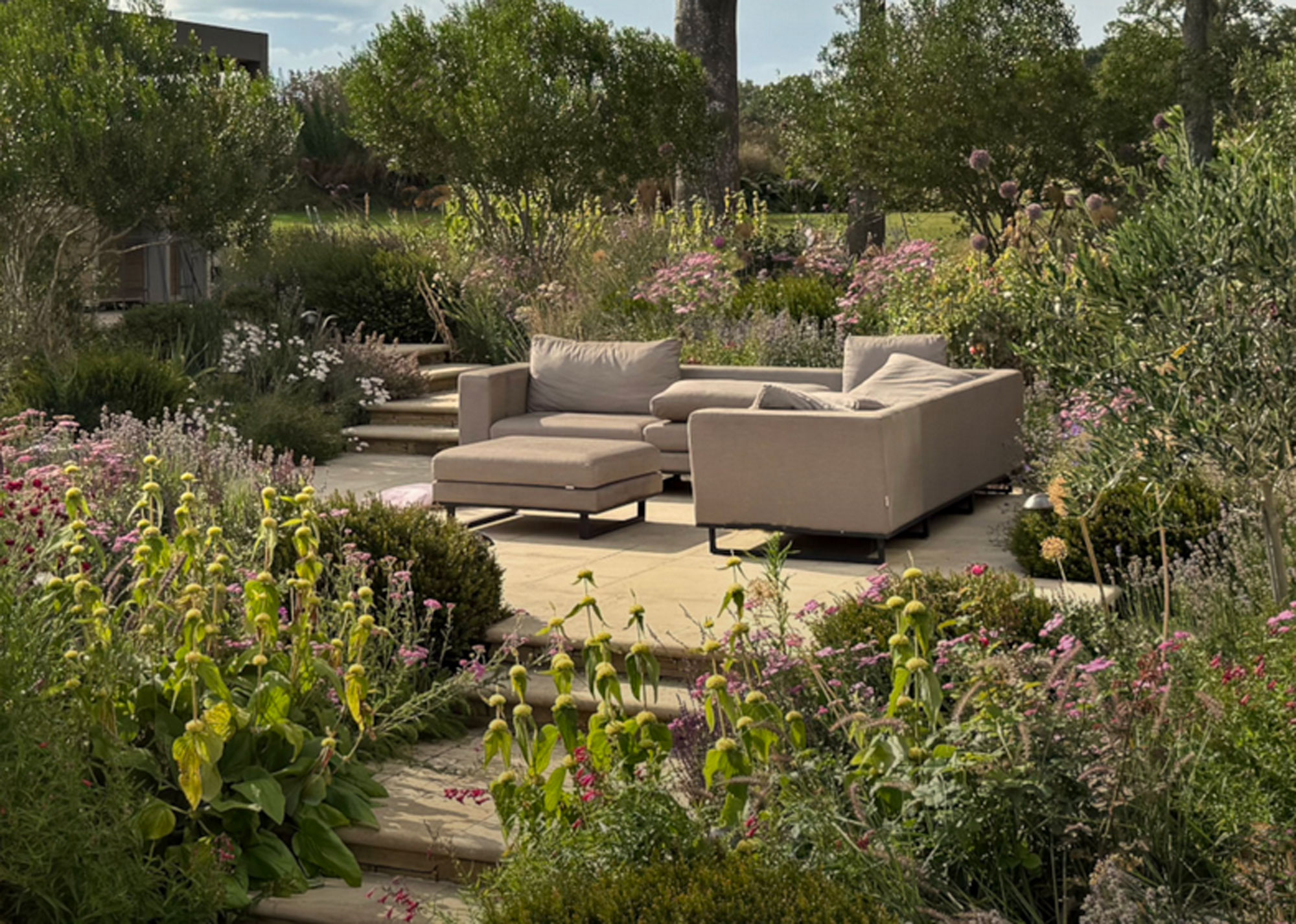 garden seating area on raised platform with steps up, surrounded by drought tolerant planting