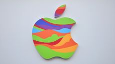 A photo of the Apple logo, formed from a rainbow of geometric shapes, against a light gray background.