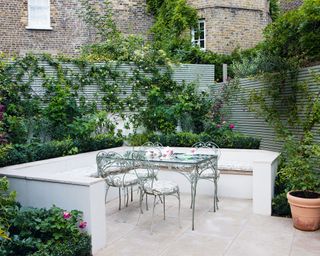 Very small front garden ideas utilising climbing plants behind a built-in seating area.