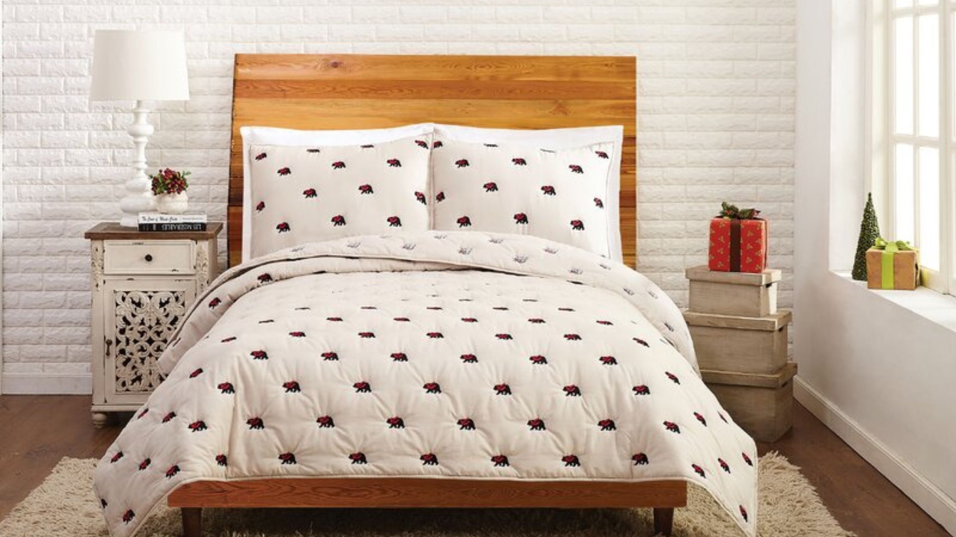 A beige Christmas bedding quilt set with embroidered bear designs on the quilt and matching shams made up on a bed.