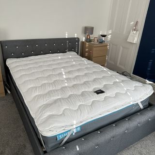 The Silentnight Airmax mattress topper on a dark grey upholstered double bed