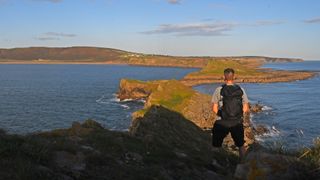 Man wearing Berghaus Remote Hike 35 on a cliff looking out to sea