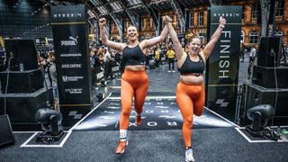 Two women celebrate as they finish a HYROX race