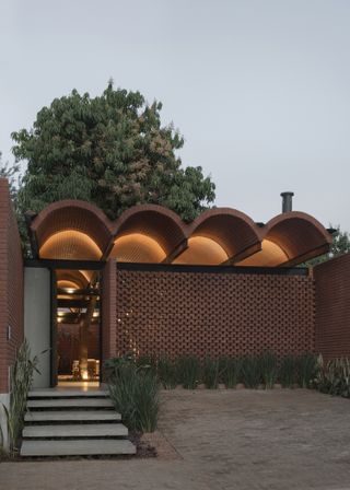 Dusk at house with vaulted brick roof and perforated wall, La Casa Intermedia
