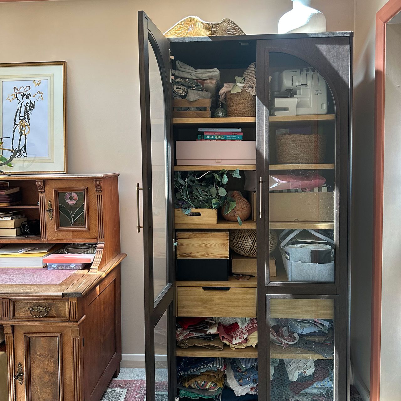 Glass fronted cabinet holding home office supplies