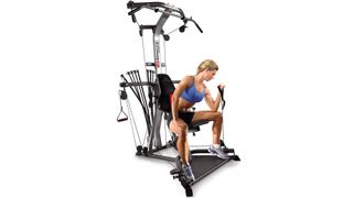 Bowflex Xtreme 2 SE review: A woman with blonde hair and wearing a blue fitness top uses the machine to workout her arms