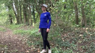 Trail runner in the woods wearing a blue top