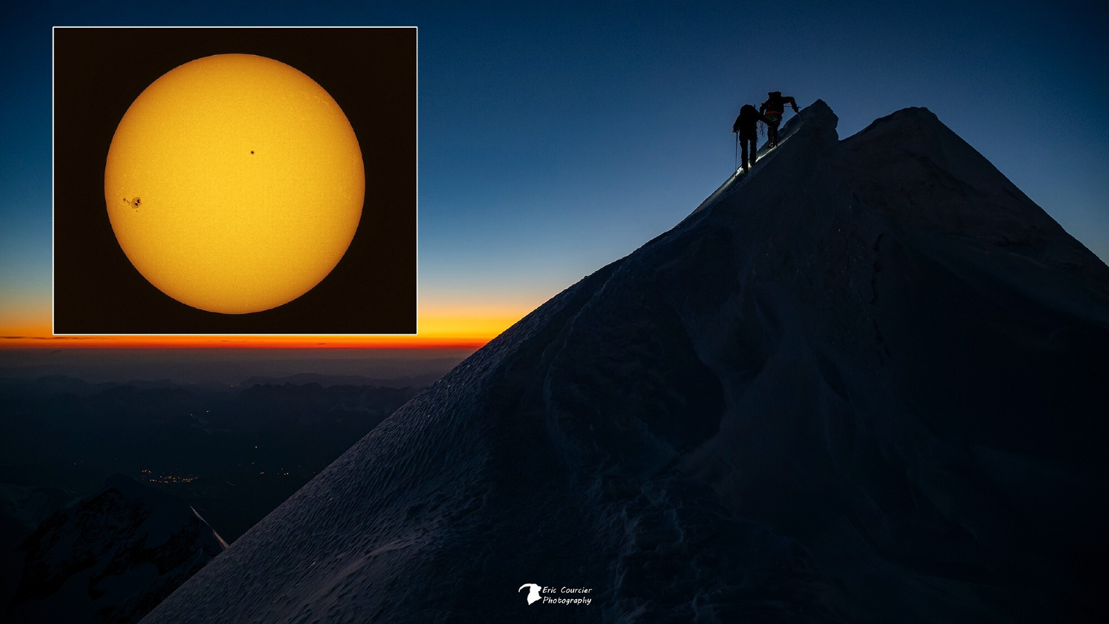 Two explorers can be seen climbing a snowy mountain peak with an orange sky close to the horizon. An image of the sun is inset at the top left of the image.